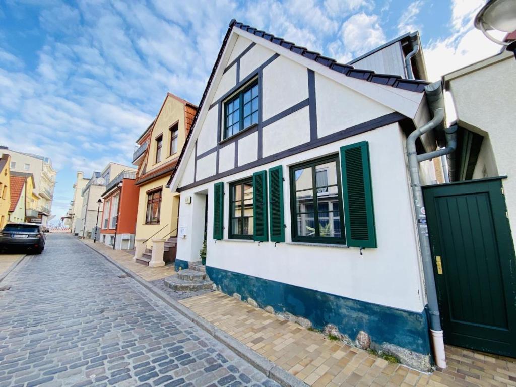 ein weißes und grünes Haus in einer Kopfsteinpflasterstraße in der Unterkunft Ferienhaus Maria in Warnemünde