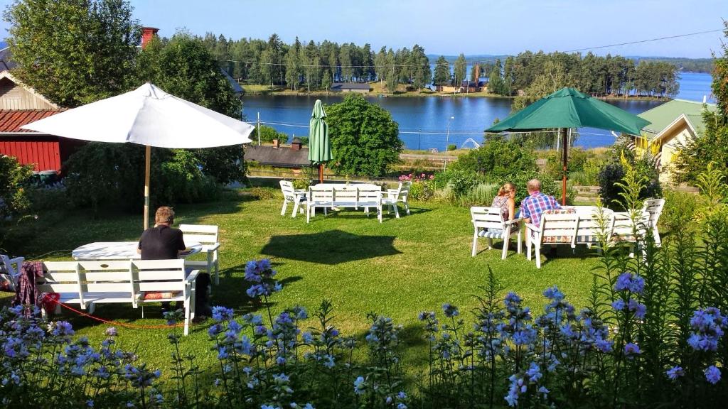 grupa ludzi siedzących w fotelach pod parasolem w obiekcie Vandrarhemmet Tallbacka/Ängelsberg Hostel w mieście Ängelsberg