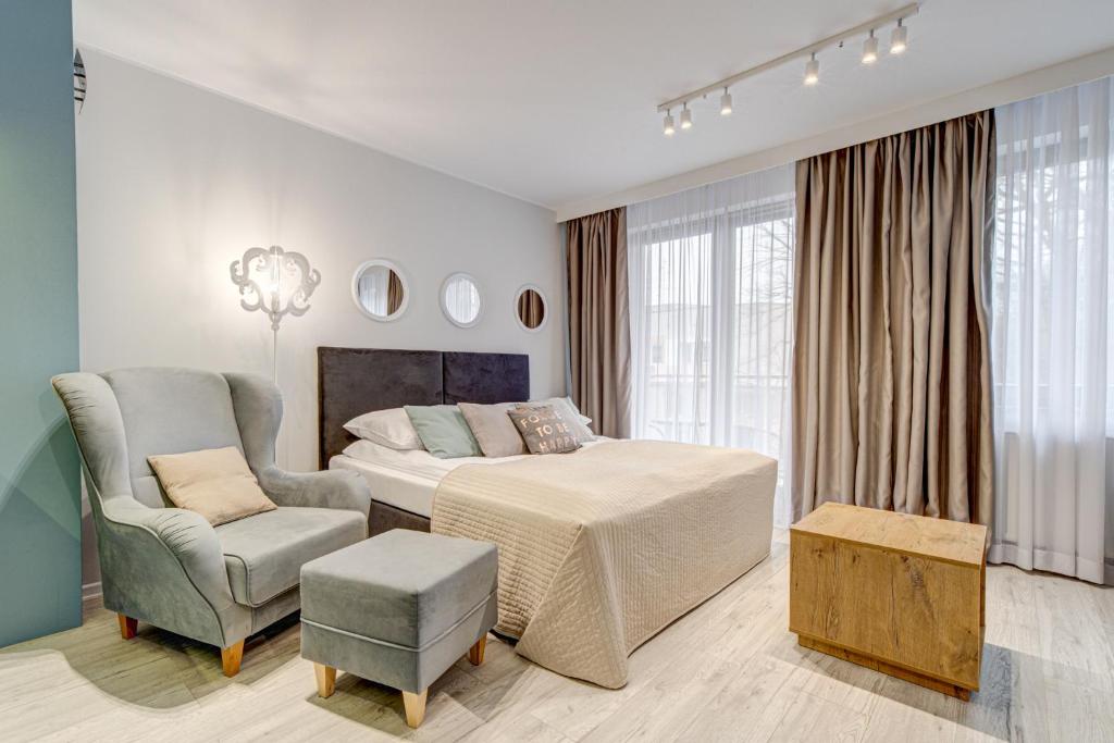 a white bedroom with a bed and a chair at Apartamenty Rondo in Świnoujście