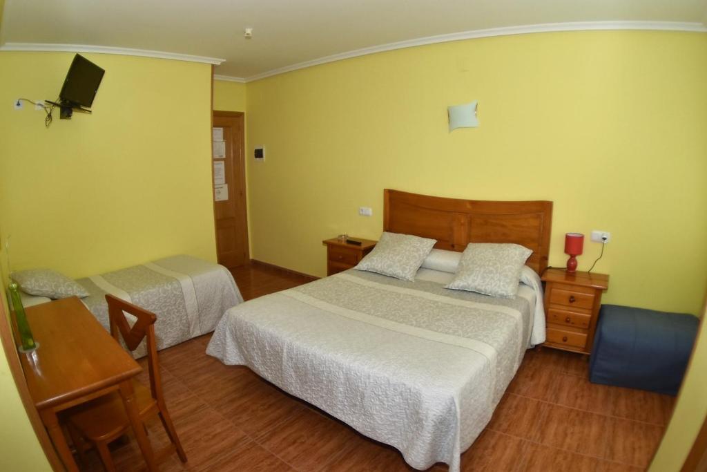 a hotel room with two beds and a television at Montaña Palentina in Guardo