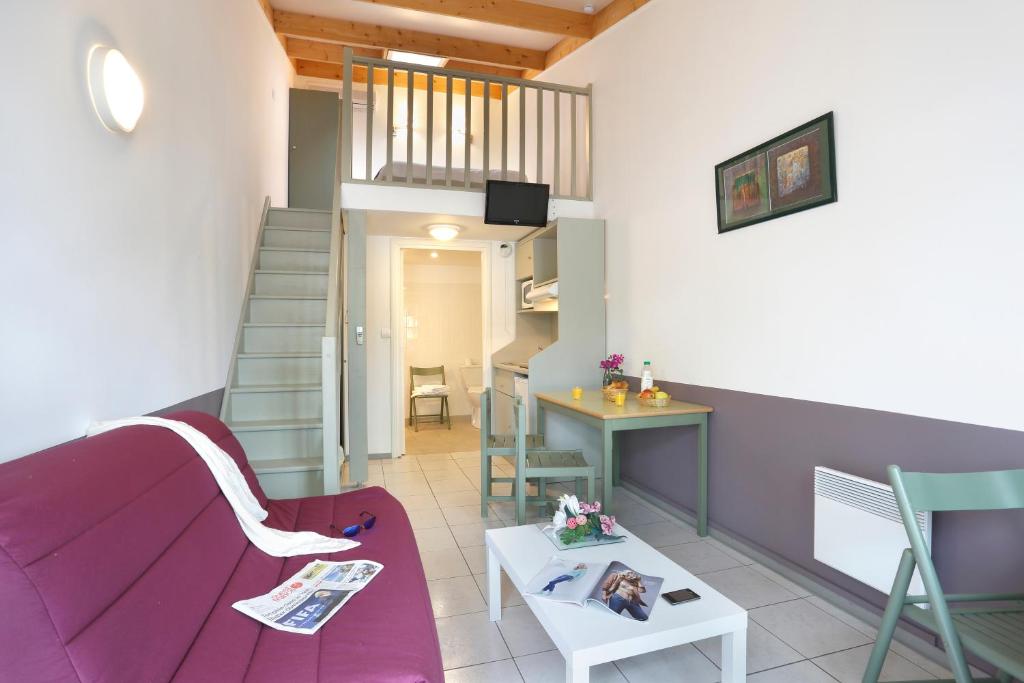 ein Wohnzimmer mit einem lila Sofa und einer Treppe in der Unterkunft Vacancéole - Résid'Price in Merville