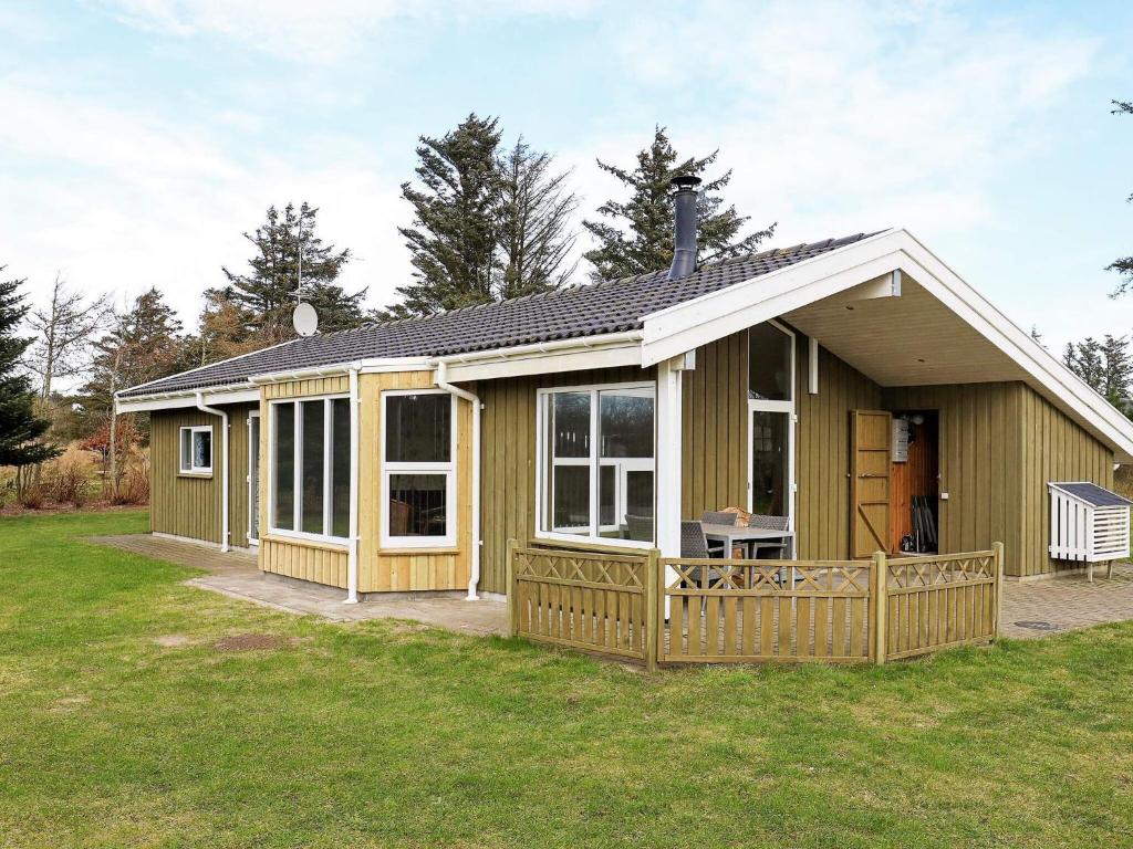 una piccola casa verde con un ampio portico di 7 person holiday home in Hj rring a Hjørring