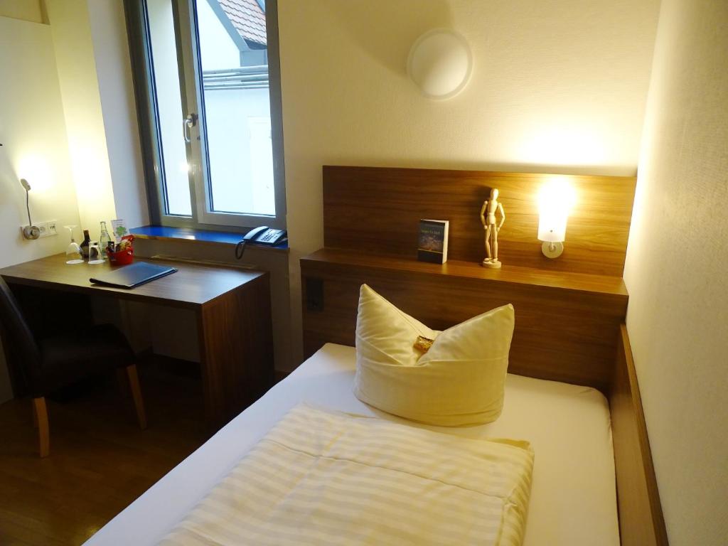 a hotel room with a bed and a desk and a laptop at Kolping-Hotel in Schweinfurt