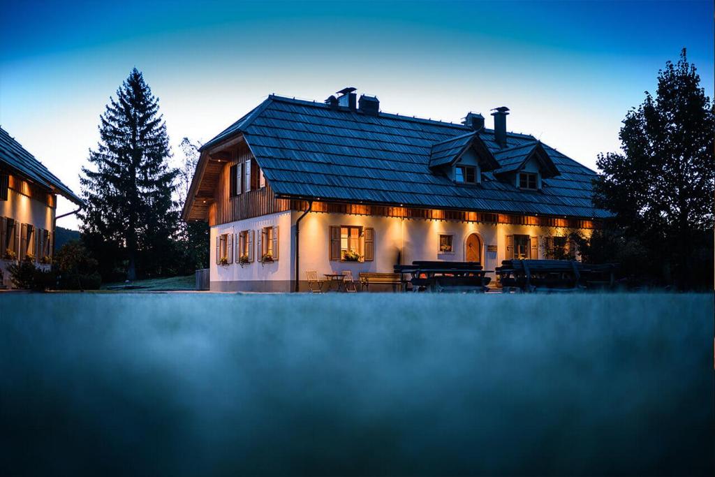 une grande maison éclairée devant elle dans l'établissement Alpine Homestead, à Goreljek
