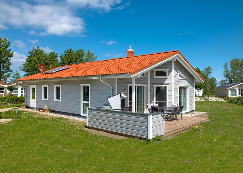 ein kleines weißes Haus mit orangefarbenem Dach in der Unterkunft Dänische Ferienhäuser am Salzhaff Haus Midsommer in Malchow