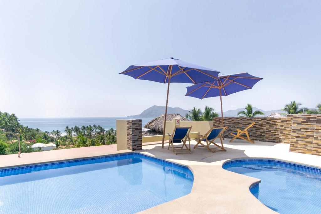 una piscina con 2 sombrillas y 2 sillas en Grand View Suites en Manzanillo