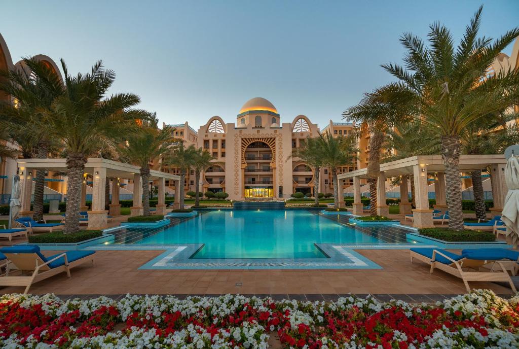 a resort swimming pool with palm trees and a building at GLOBALSTAY at Sarai Apartments Beachfront Paradise with Pool and Gym in Dubai