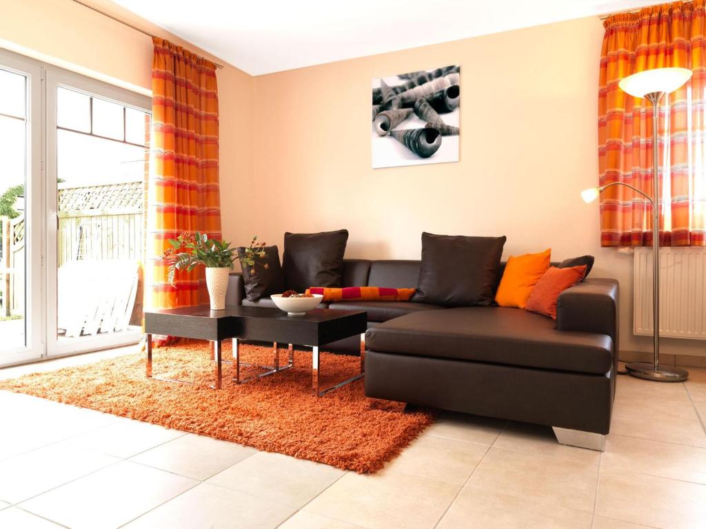 ein Wohnzimmer mit einem schwarzen Sofa und einem Tisch in der Unterkunft Reihenhäuser Timmendorf Strand Haus Utkiek in Timmendorf