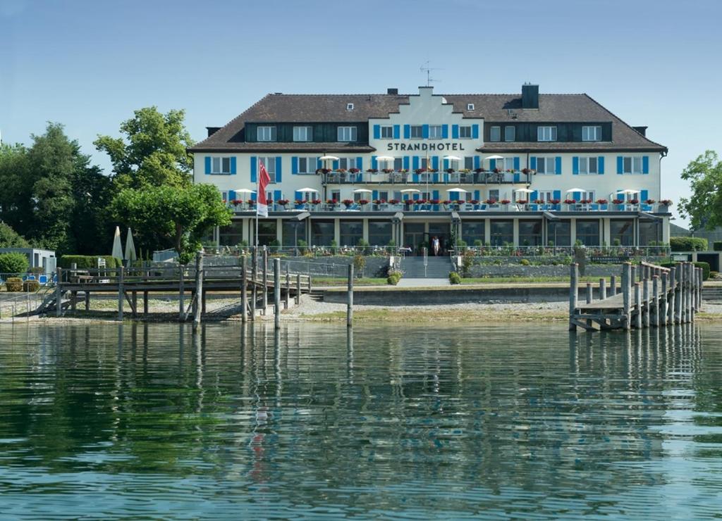 ein großes Gebäude am Ufer eines Wasserkörpers in der Unterkunft Strandhotel Löchnerhaus in Reichenau