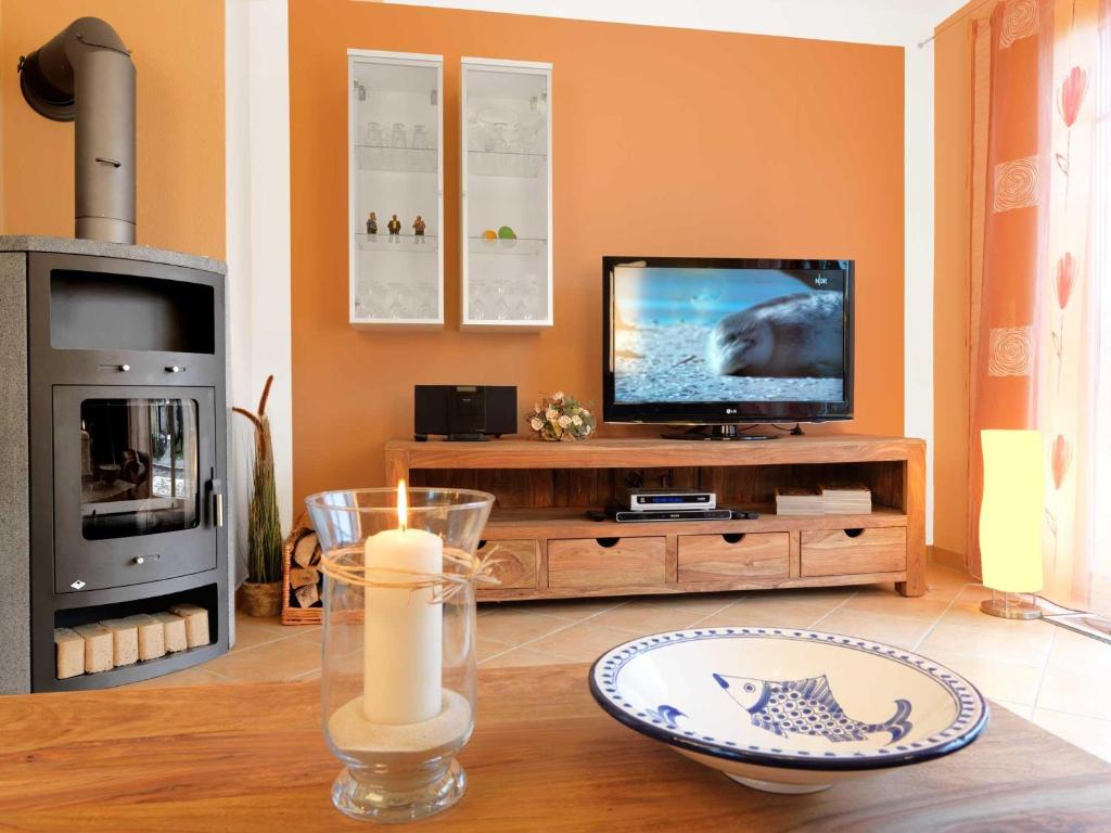 a living room with a television and a table with a candle at Doppelhäuser Timmendorf Strand Haus Ruh di ut in Timmendorf