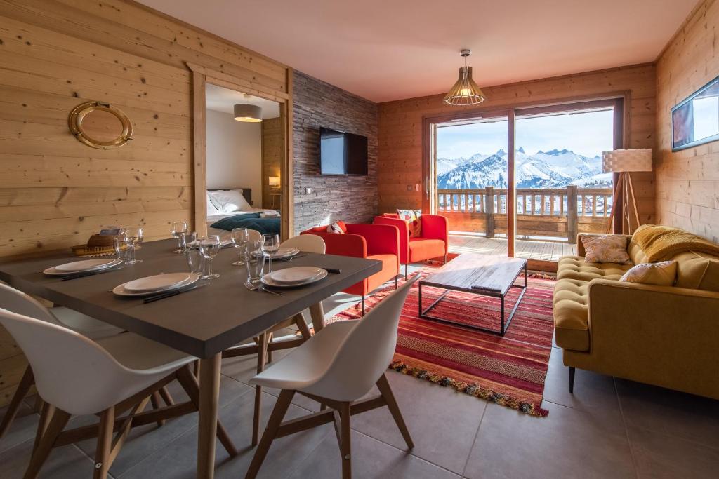 a dining room with a table and chairs and a couch at ODYSSEE B102 Cosy appartement sur les pistes in La Toussuire