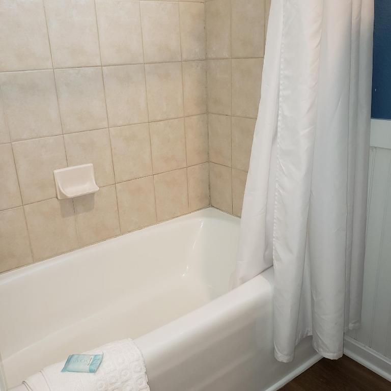 a white bath tub with a shower curtain in a bathroom at Avenue Inn & Spa in Rehoboth Beach