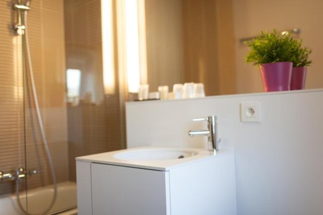 y baño blanco con lavabo y ducha. en Hotel La Passerelle en Grandhan