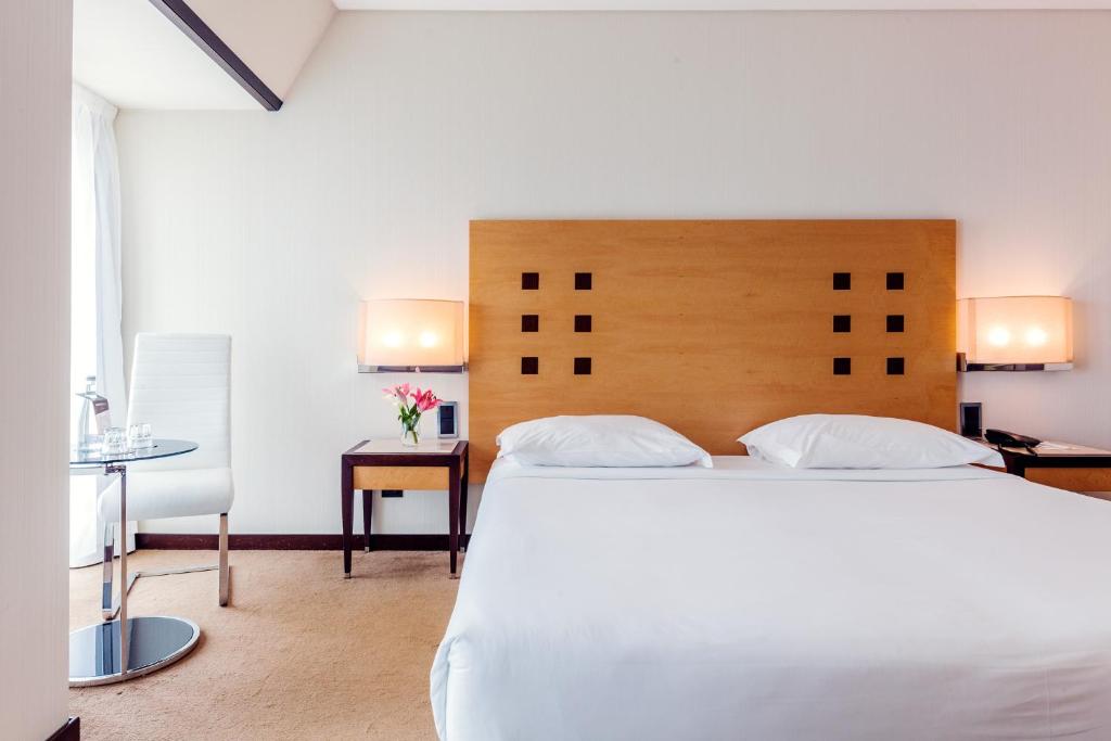 een slaapkamer met een groot wit bed en een bureau bij Hotel Lux Fatima in Fátima