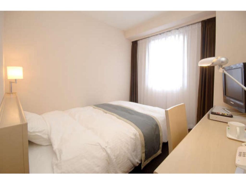 Hotel Frontier Iwaki / Vacation STAY 79262 في إيواكي: غرفة نوم بسرير ومكتب مع تلفزيون