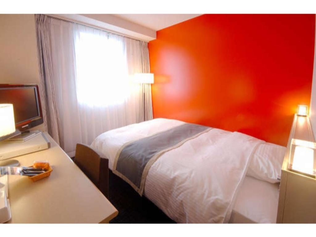 いわき市にあるHotel Frontier Iwaki / Vacation STAY 79264のベッド、デスク、窓が備わるホテルルームです。