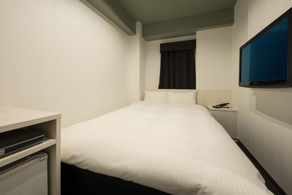 um quarto com uma cama branca e uma televisão de ecrã plano em Nagoyaeki Access Hotel / Vacation STAY 79747 em Nagoia