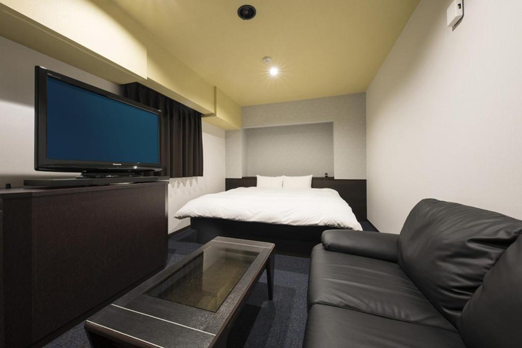 a room with a couch and a tv and a bed at Nagoyaeki Access Hotel / Vacation STAY 79749 in Nagoya