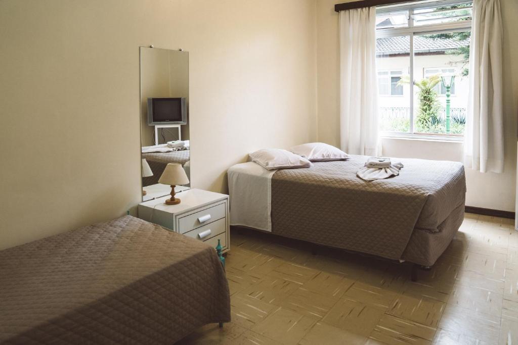 a bedroom with two beds and a mirror at Pousada Betânia in Curitiba