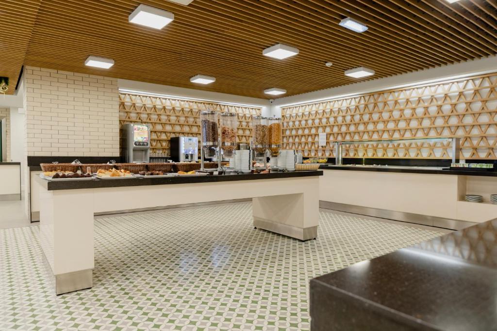 A bright buffet room presents food counters beneath a slatted wood ceiling.
