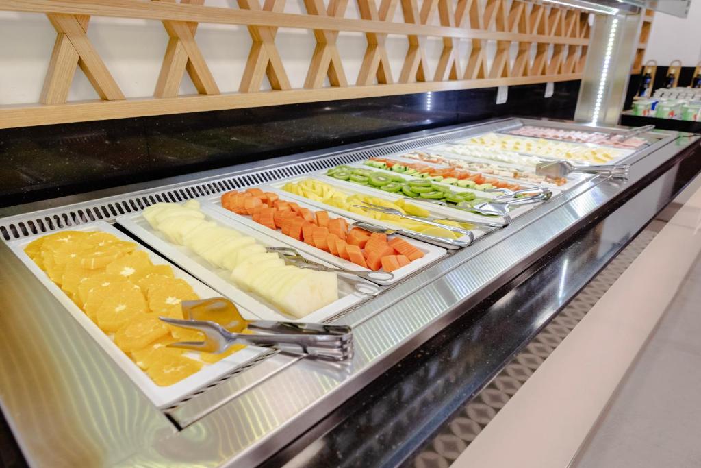 A chilled buffet displays sliced fruit and serving tongs.
