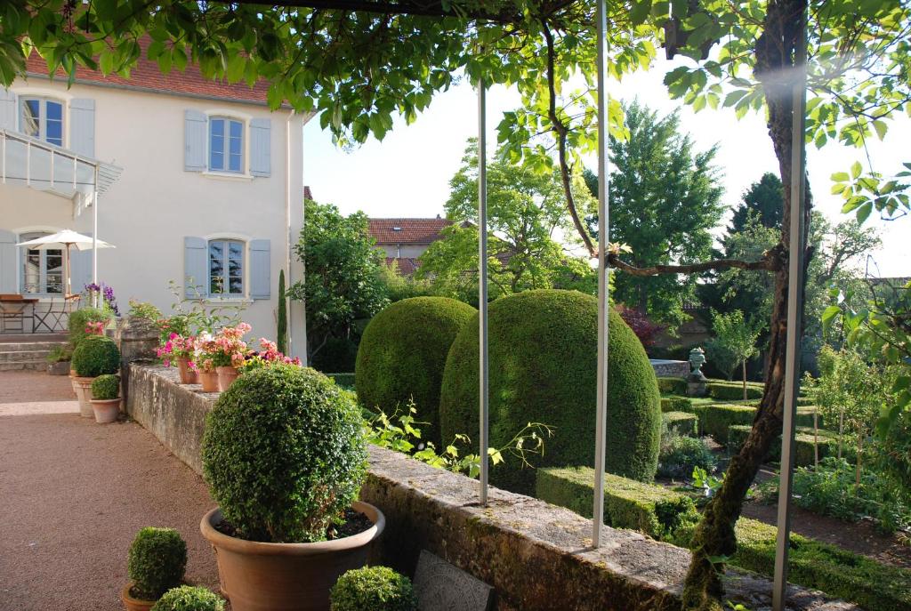 a garden with bushes and trees and a building at Demeure Bouquet in Ambierle