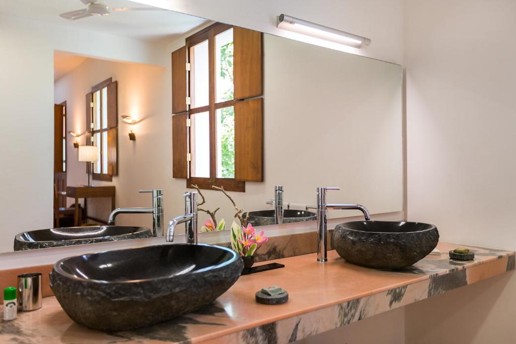 a bathroom with two sinks and two mirrors at Villa Shanti - Heritage Hotel for Foodies in Puducherry