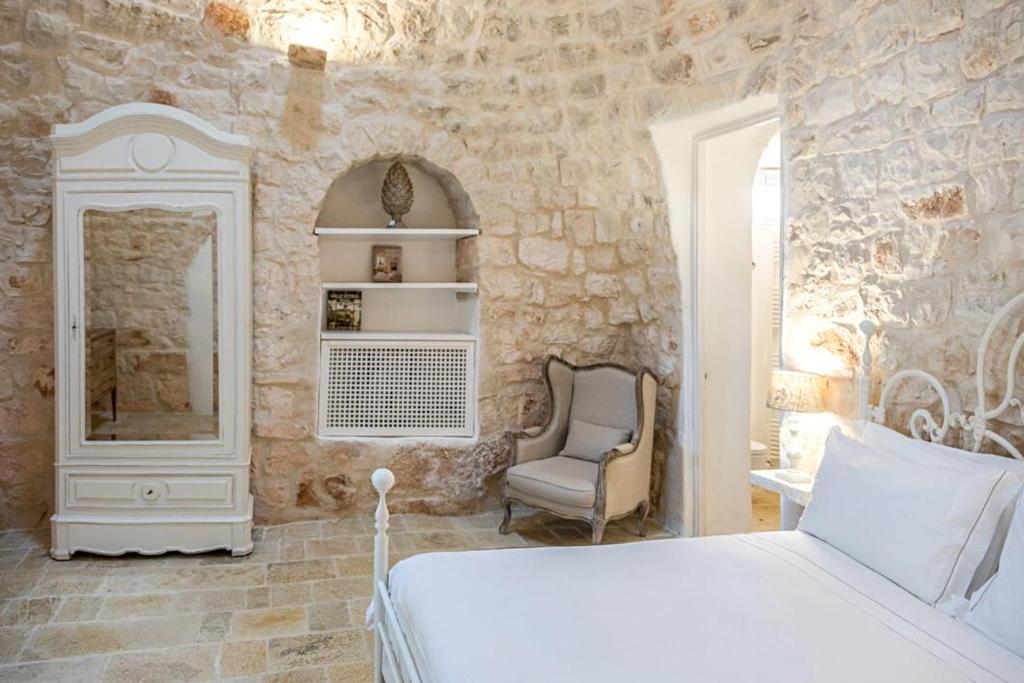een slaapkamer met een bed, een stoel en een spiegel bij Borgo Fantese in Ostuni
