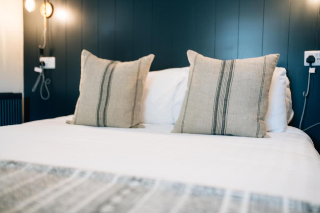 a large white bed with pillows on it at The Fullerton Arms in Ballintoy