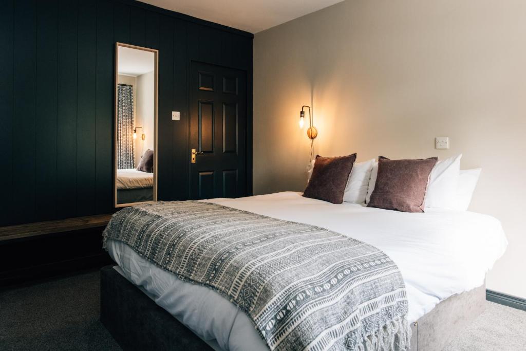 a bedroom with a large white bed and a mirror at The Fullerton Arms in Ballintoy