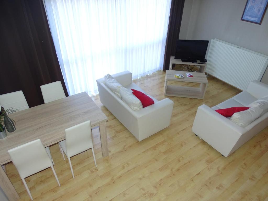een woonkamer met een tafel en witte stoelen bij Ambassador Suites Leuven in Leuven