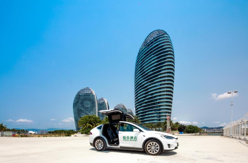 三亜市にあるSanya Phoenix Island Yuejia flatの高層ビルの前に停車する白い電気自動車