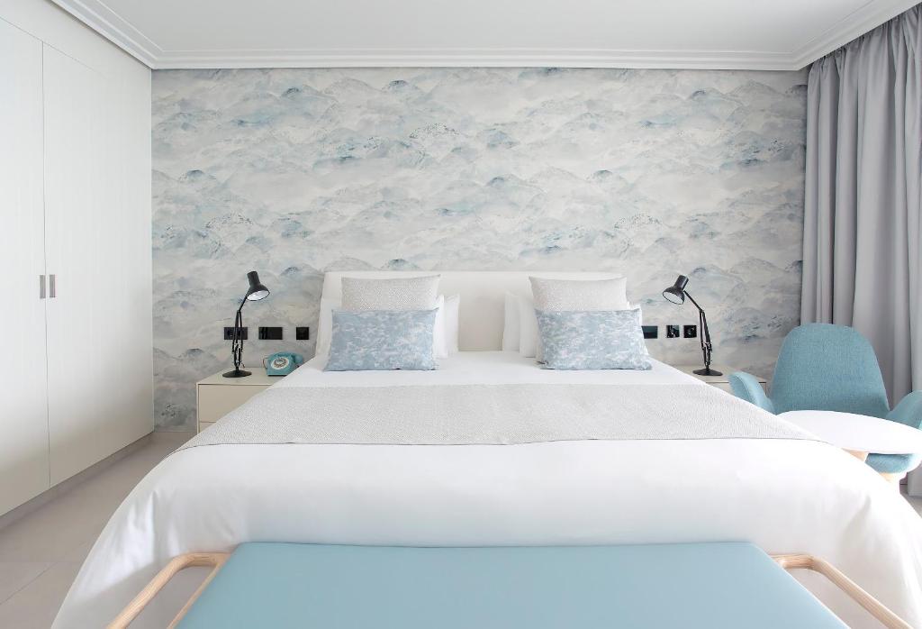 a bedroom with a large white bed and blue chairs at Hotel Lava Beach in Puerto del Carmen