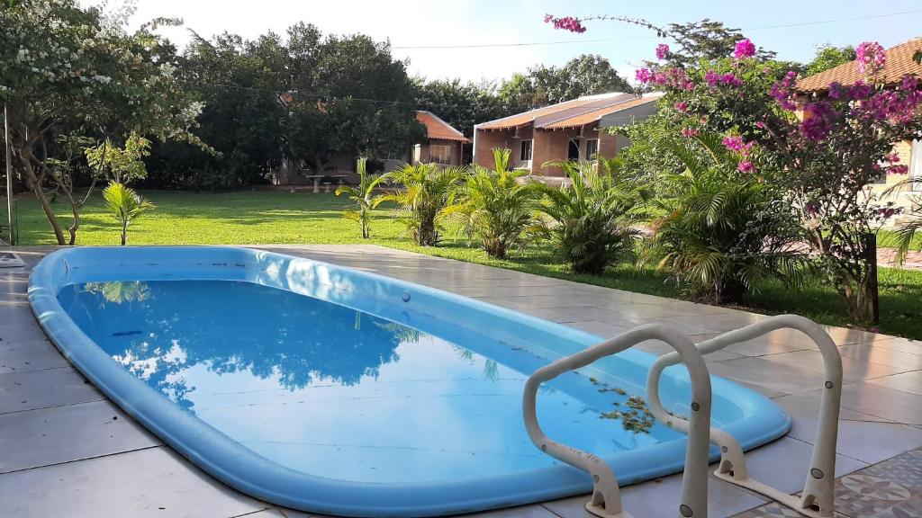 a blue pool with a chair next to a yard at Chacara Manaca da Serra in Chapada dos Guimarães