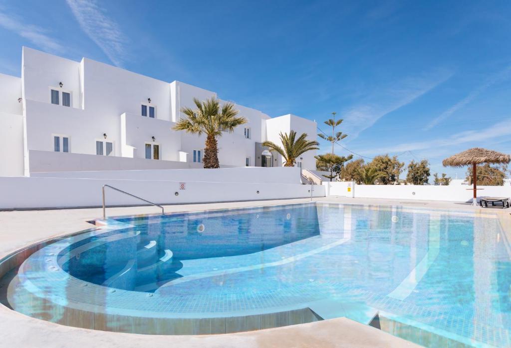 a large swimming pool in front of a white building at Nikos Hotel in Karterados