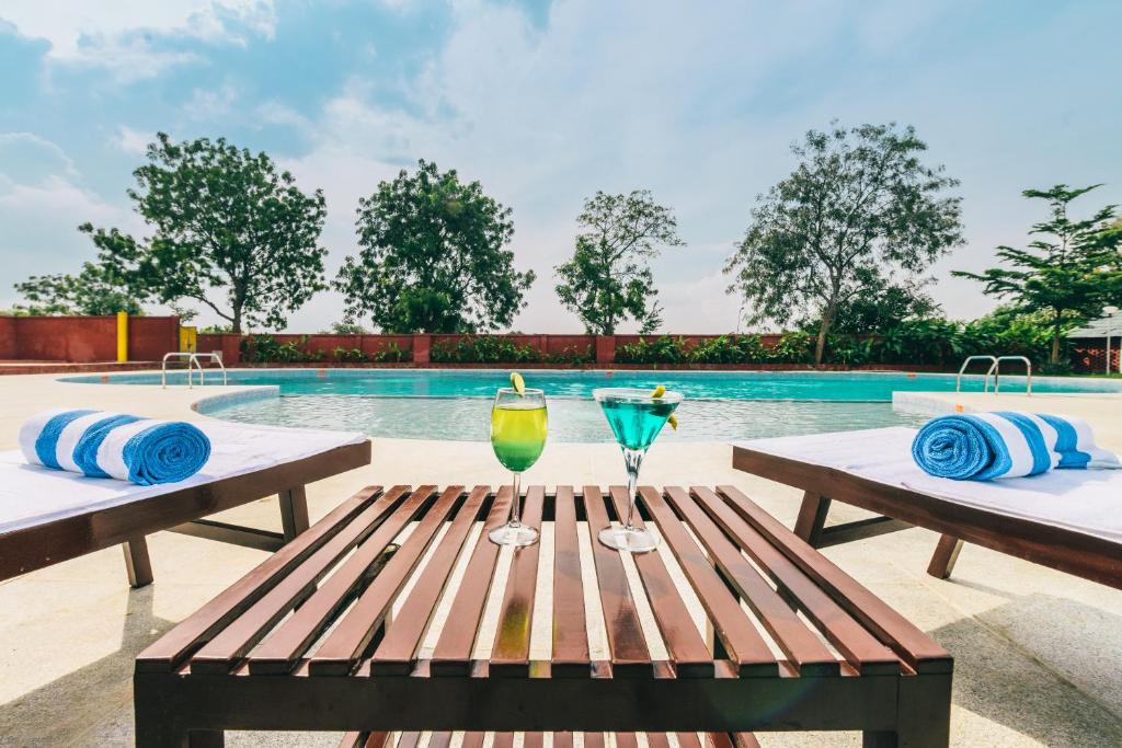 a table with two drinks on it next to a swimming pool at Trance Greenfields Resort and Convention Centre in Venkatāpur