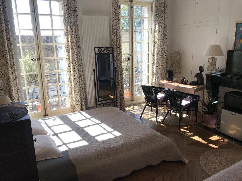 a bedroom with a bed and a desk and windows at Chambre d'hôte du Château in Dourdan