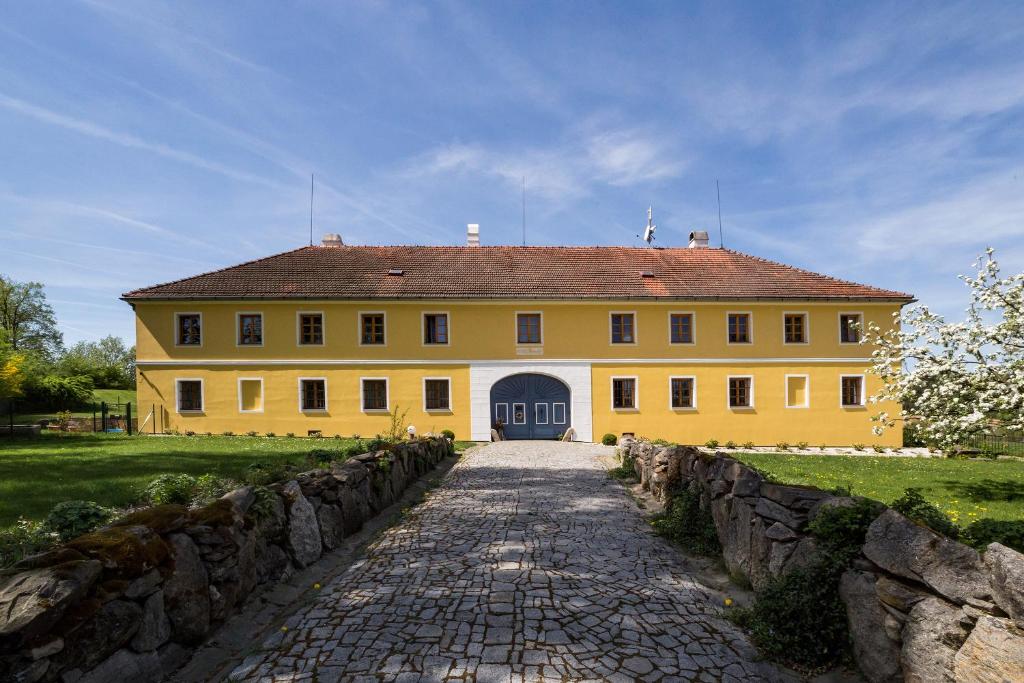 uma grande casa amarela com um caminho de pedra em frente em Apartmán Zahrádka em Mírkovice