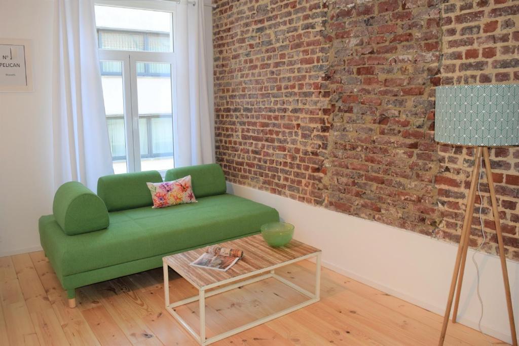 un sofá verde en una habitación con una pared de ladrillo en Home Sweet Home Brussels center, en Bruselas