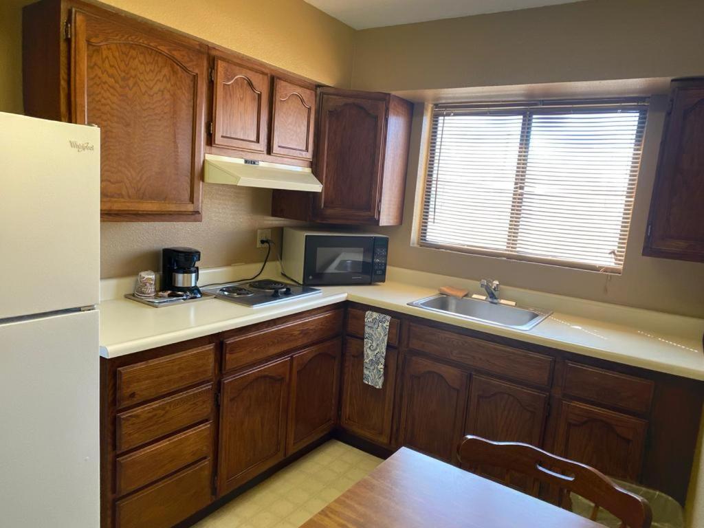 a kitchen with wooden cabinets and a sink and a refrigerator at royal inn in Lovelock