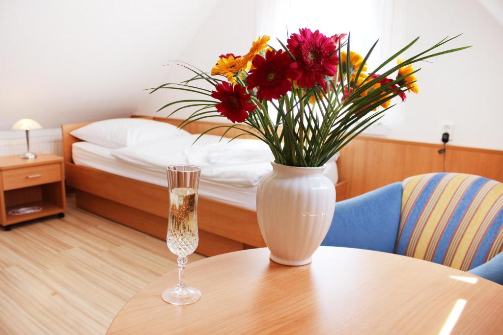 a vase with flowers on a table with a bed at Hotel Pension Kirschstein in Wolgast