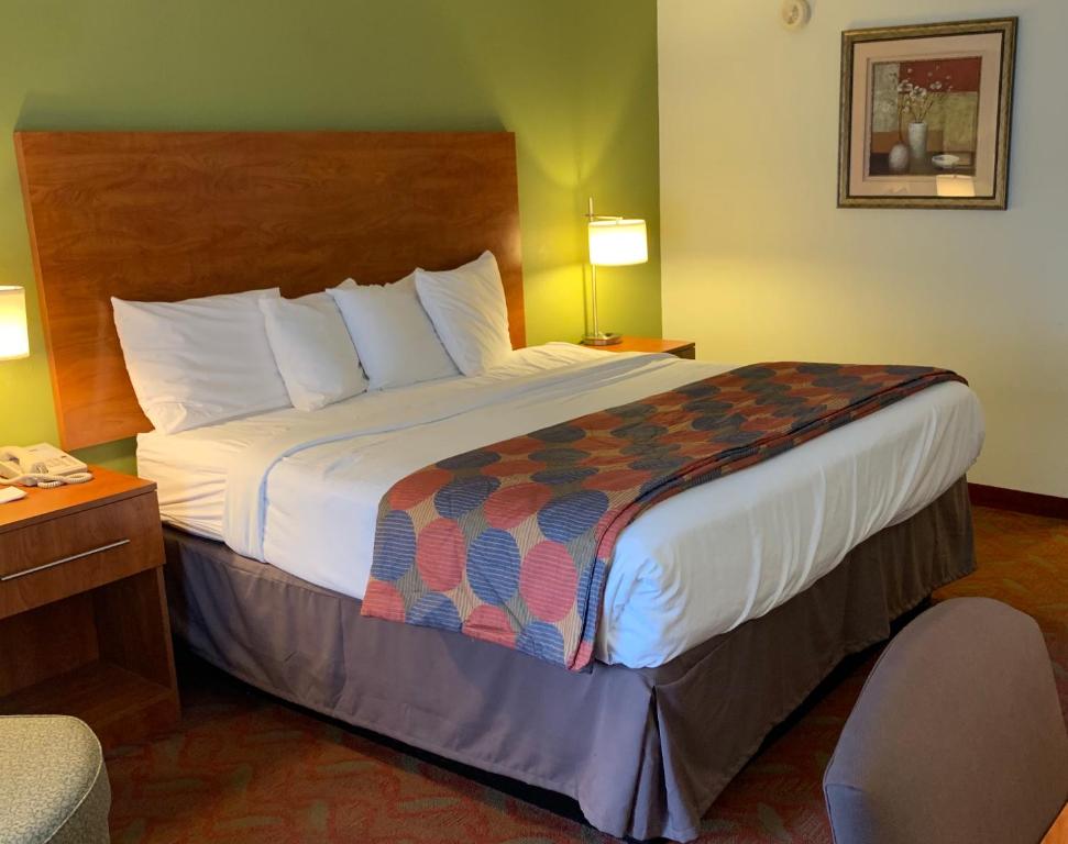 a hotel room with a large bed and a chair at Baymont by Wyndham Cave City in Cave City