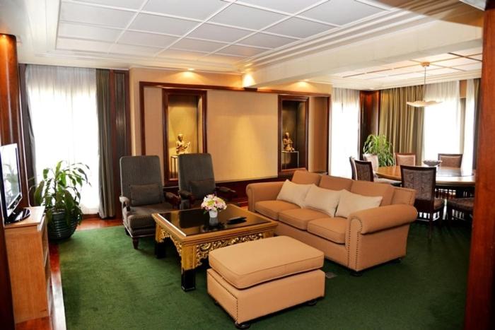 A spacious traditional sitting room with sofas, armchairs, a television and a dining area.