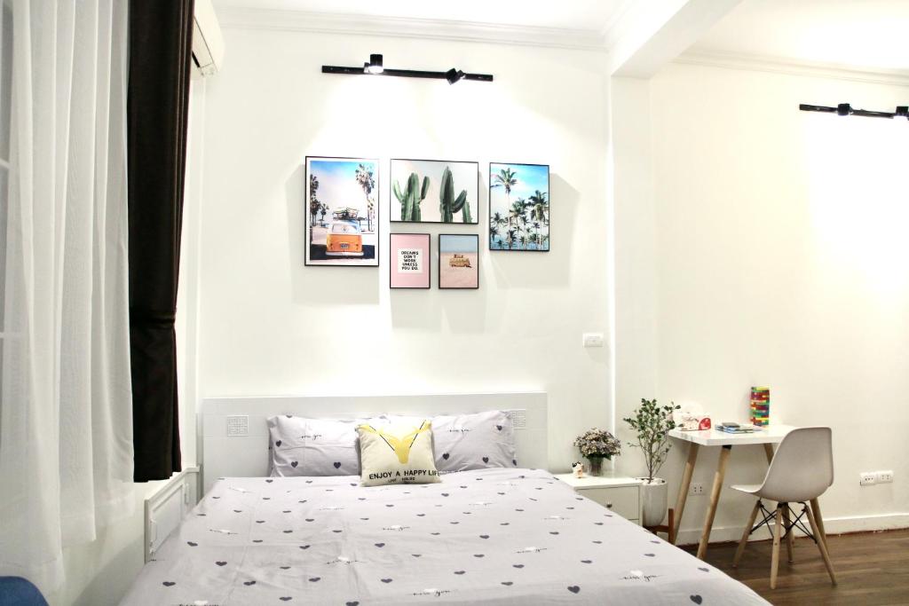ハノイにあるVitamin Home Hoàn Kiếmの白いベッドルーム(ベッド1台付)が備わります。壁には絵画が飾られています。