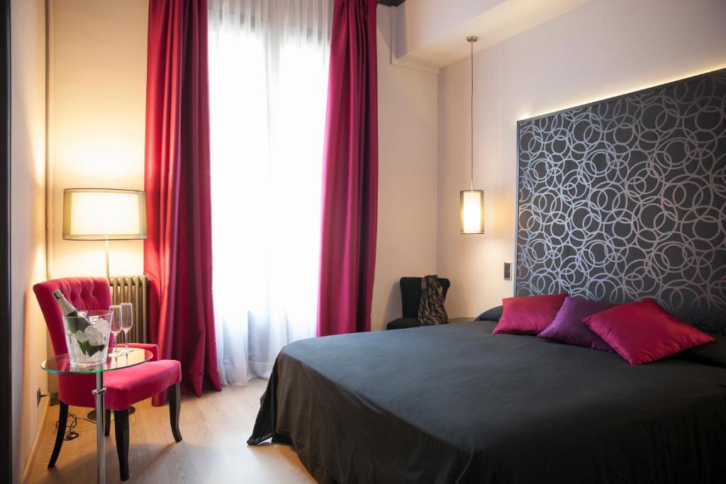 バルセロナにあるウンマ バルセロナ B＆B ブティックのベッドルーム1室(ベッド1台付)、赤いカーテン付きの窓が備わります。