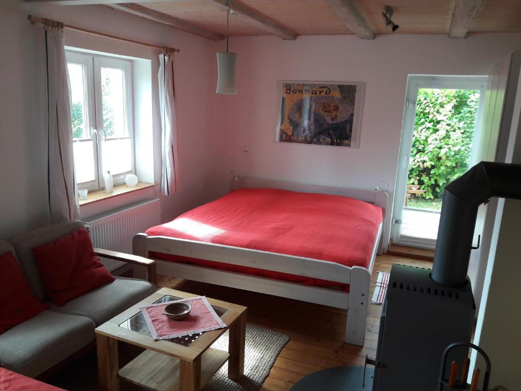 ein kleines Zimmer mit einem roten Bett und einem Sofa in der Unterkunft Öko-Ferienwohnung-Kiel Sturmmöwe in Kiel