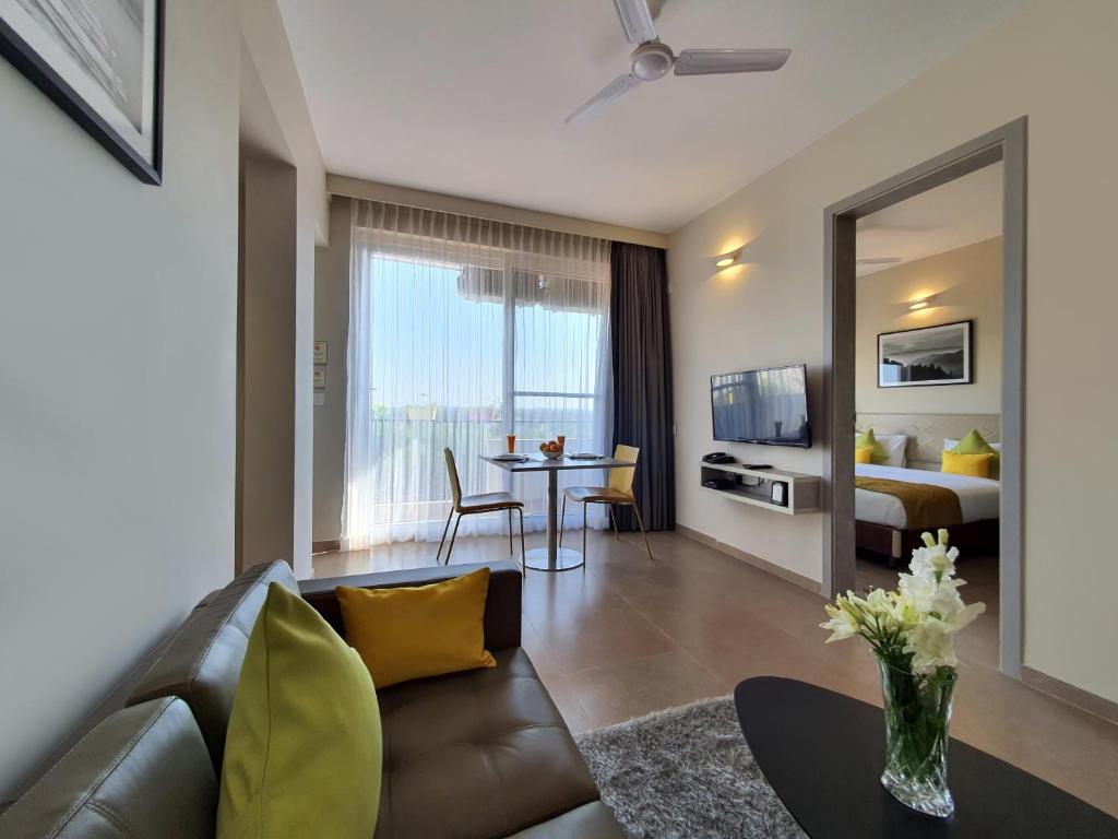 a living room with a couch and a bedroom at Hotel Avora Tree By Rivido Kempegowda Airport Road in Bangalore