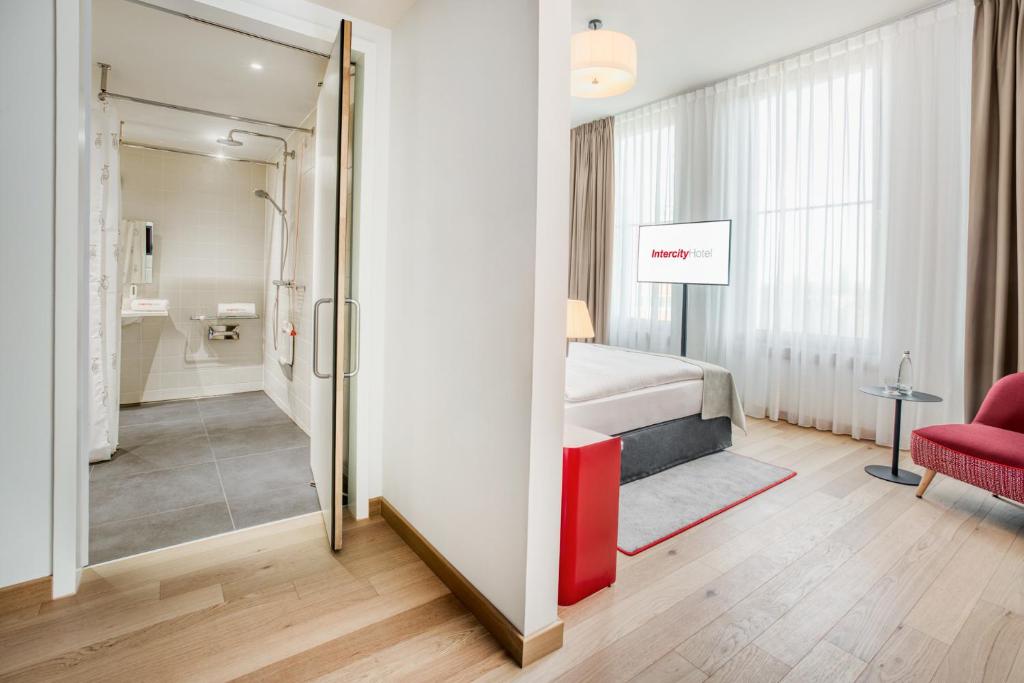 a bedroom with a bed and a red chair at IntercityHotel Hamburg-Barmbek in Hamburg