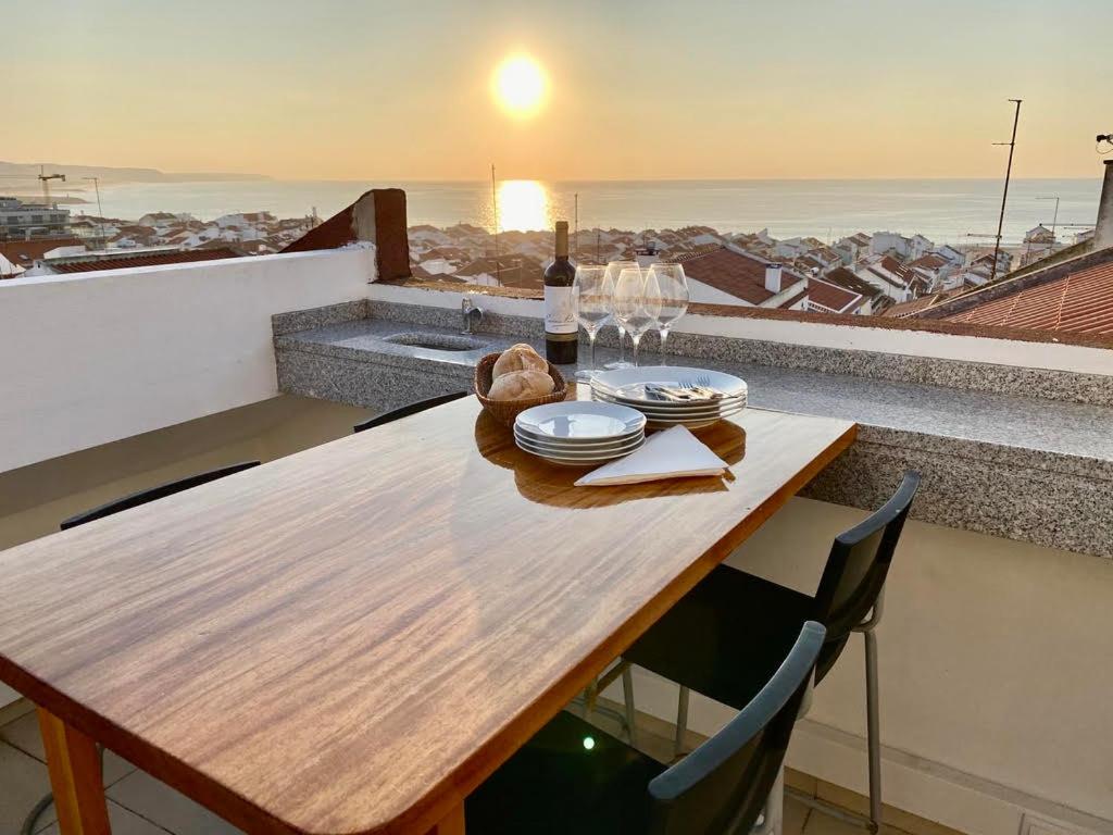 einen Holztisch mit einer Flasche Wein auf dem Balkon in der Unterkunft Sea Breeze Apartments - 100m to Beach By Silver Prop in Nazaré