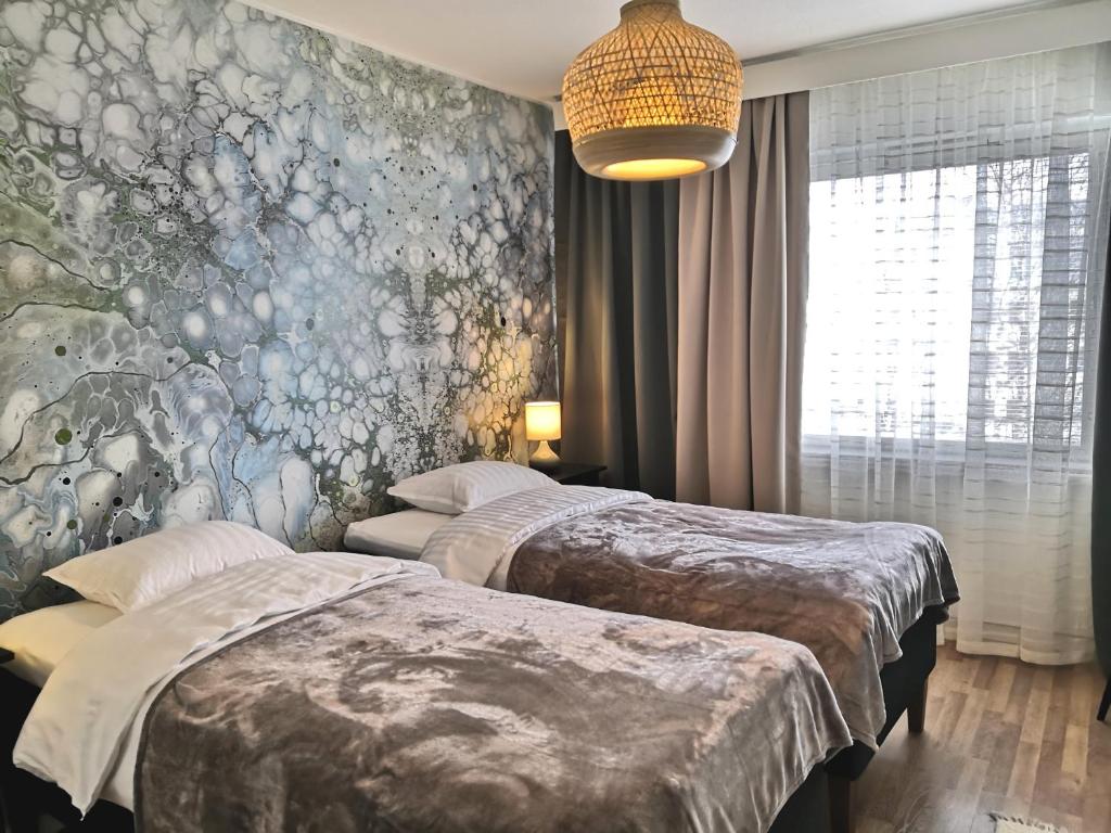 クオピオにあるCity Apartment Savonkatuのベッドルーム1室(ベッド2台付)が備わります。壁に壁画が飾られています。